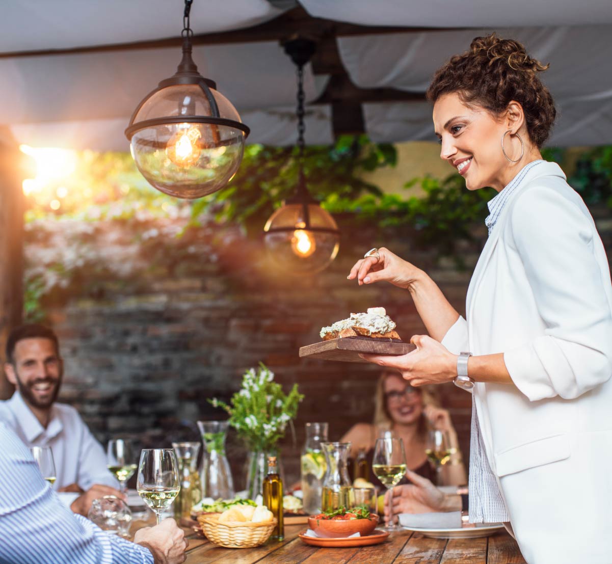 A woman hosting an outdoor dinner party, giving bak to her community.