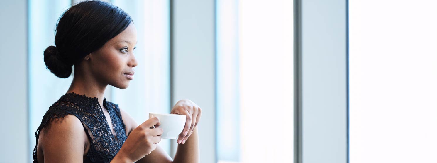 A woman in a professional setting holding a cup of coffee