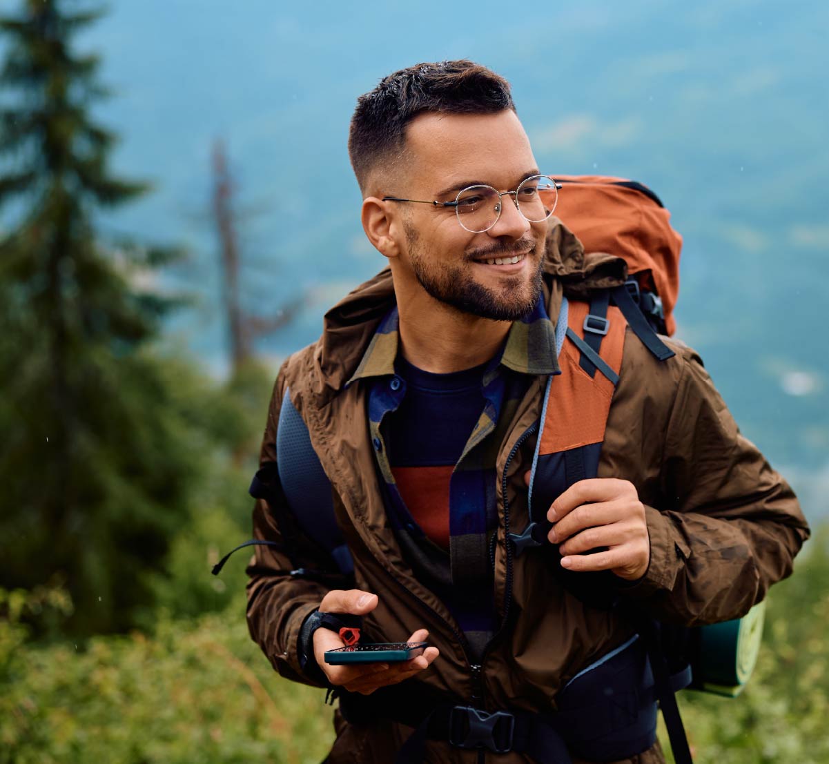 A happy young man backpacking in an evergreen forest.