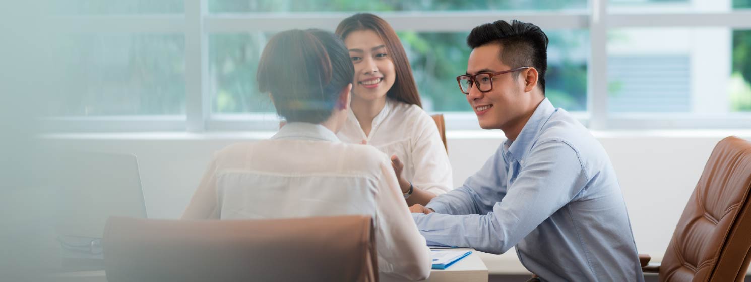 Young professionals smiling while gathered at a desk.