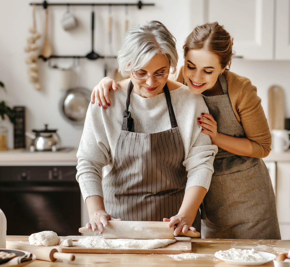 An older woman and a younger woman baking together in a home kitchen.