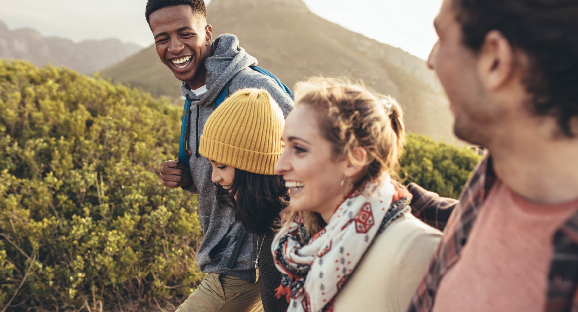 A group of four friends smiling as they walk outside.