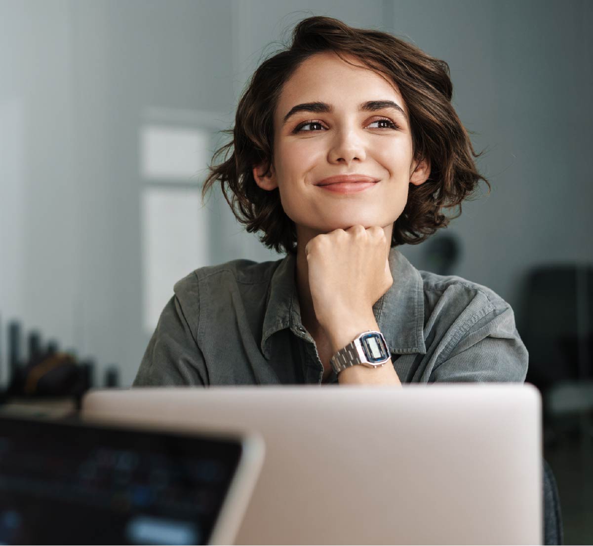 A professional woman sitting behind a laptop and smiling