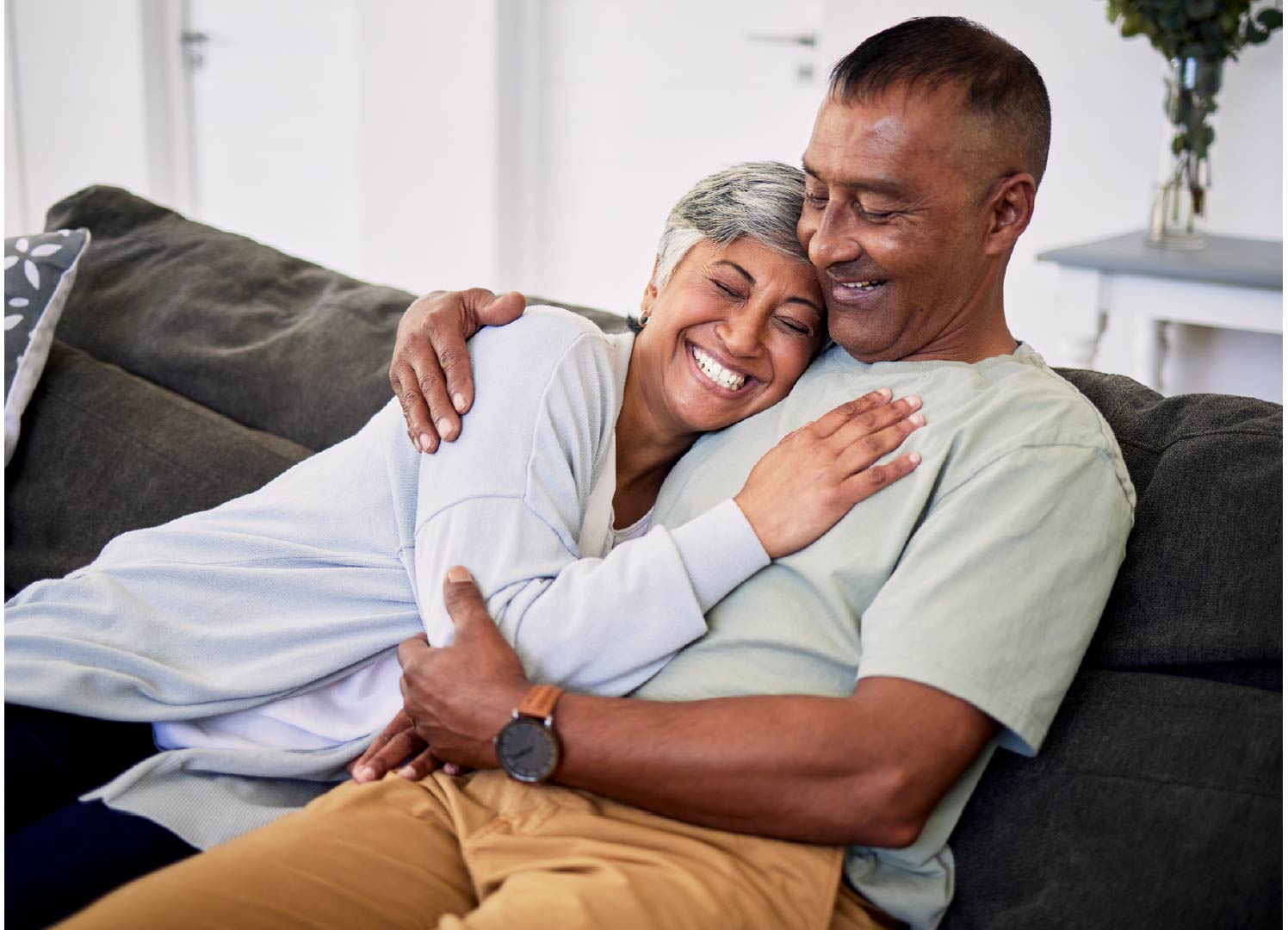 An older couple laughing and cuddling on a couch