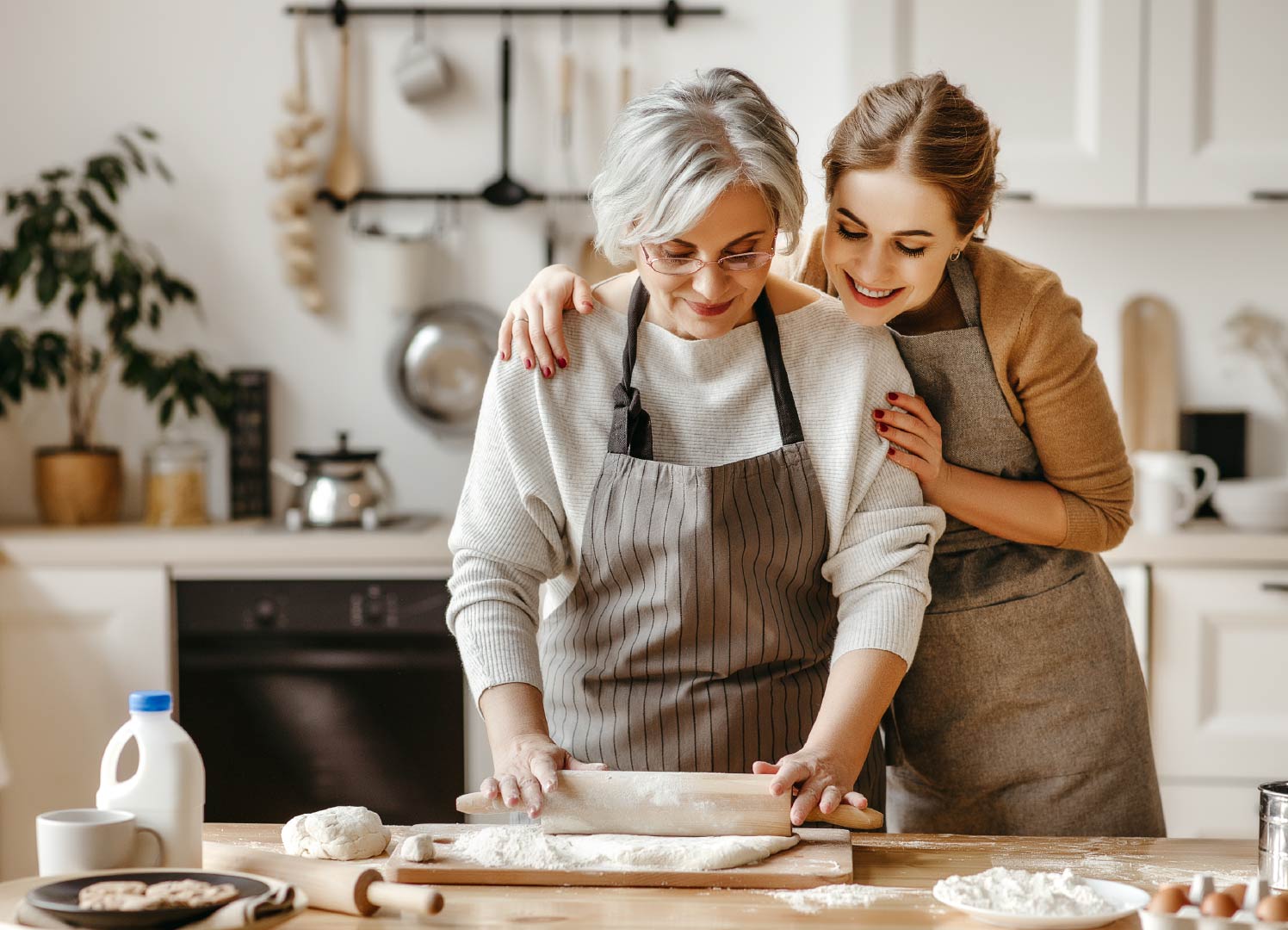 An older woman and a younger woman baking together.