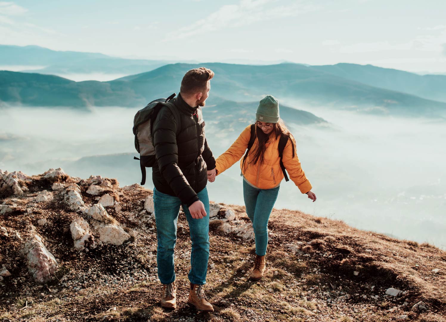 A couple holding hands and climbing a mountain.