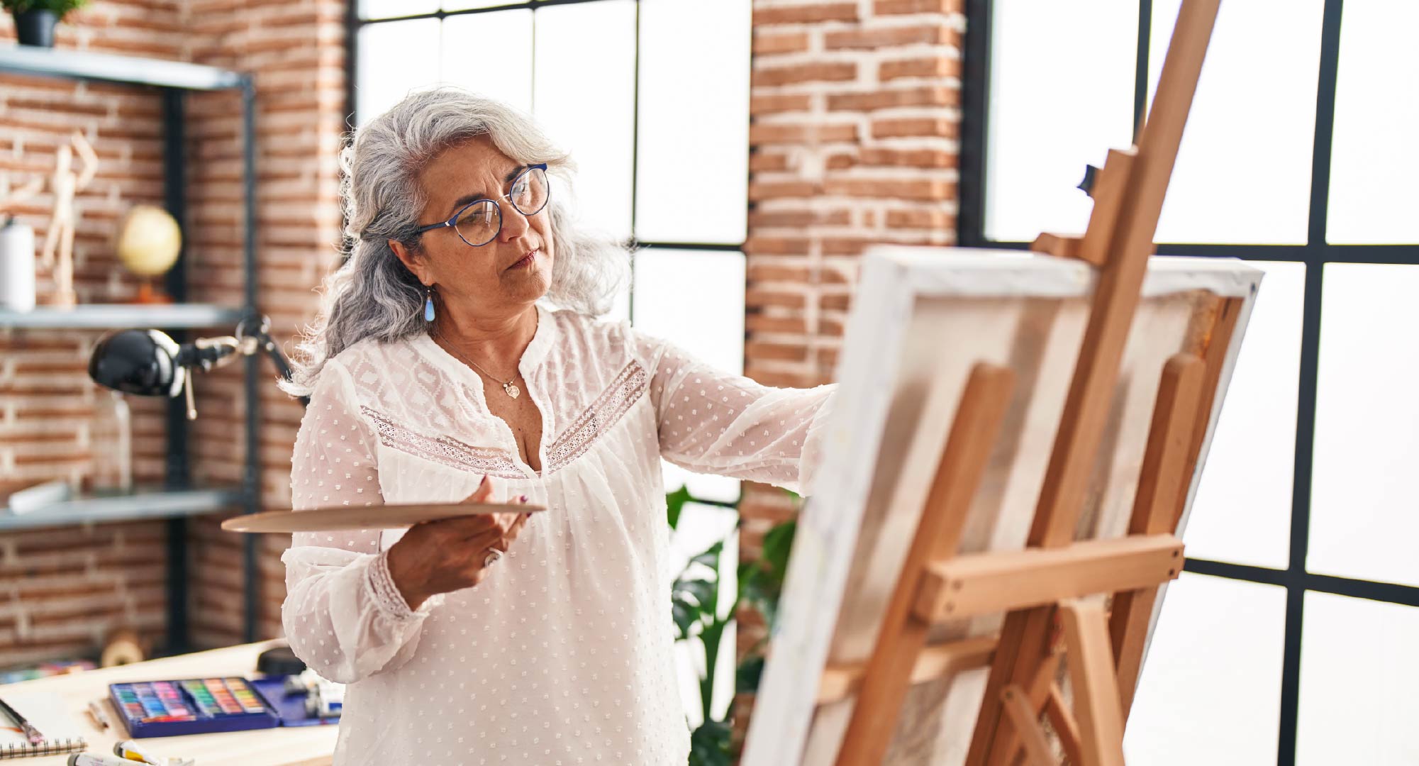 An older woman painting on canvas