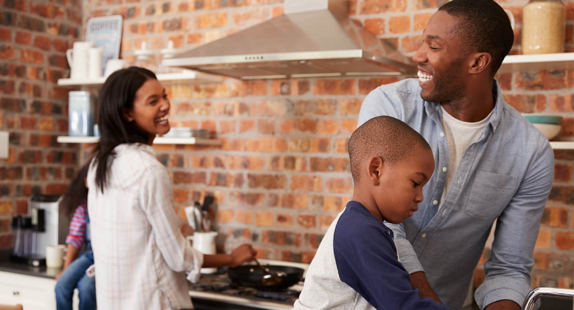 A mom, dad, and child happily cooking in the kitchen.