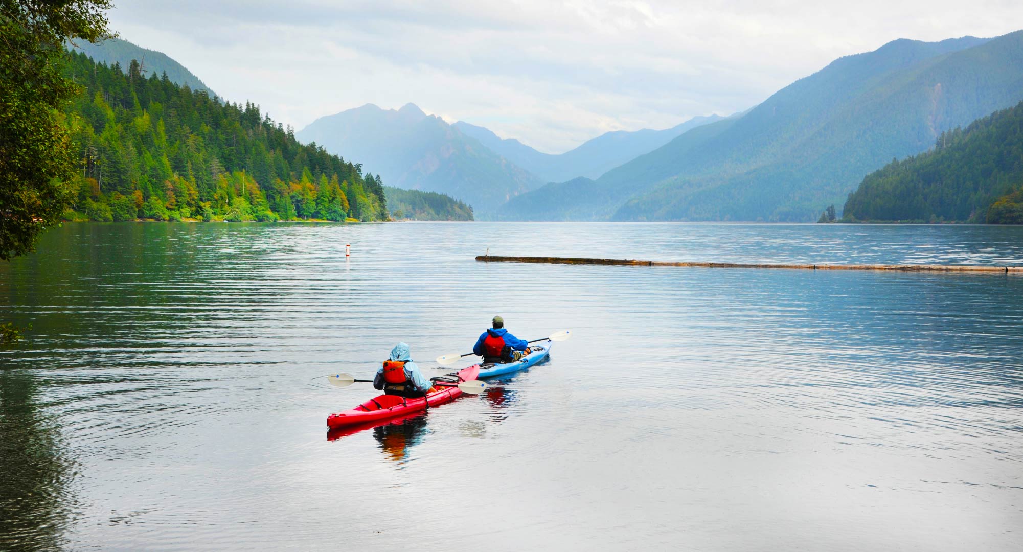 Two kayakers on a lake surrounded by mountains